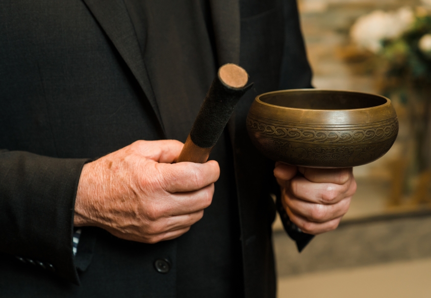 white hand holding a singing bowl used in meditation