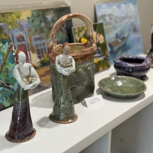 two female figures and two bowls made of clay sitting on a white bookcase