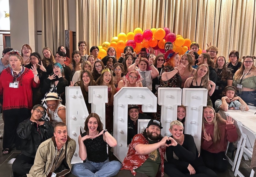 Group of enthusiastic young adults with balloons and NGU sign.