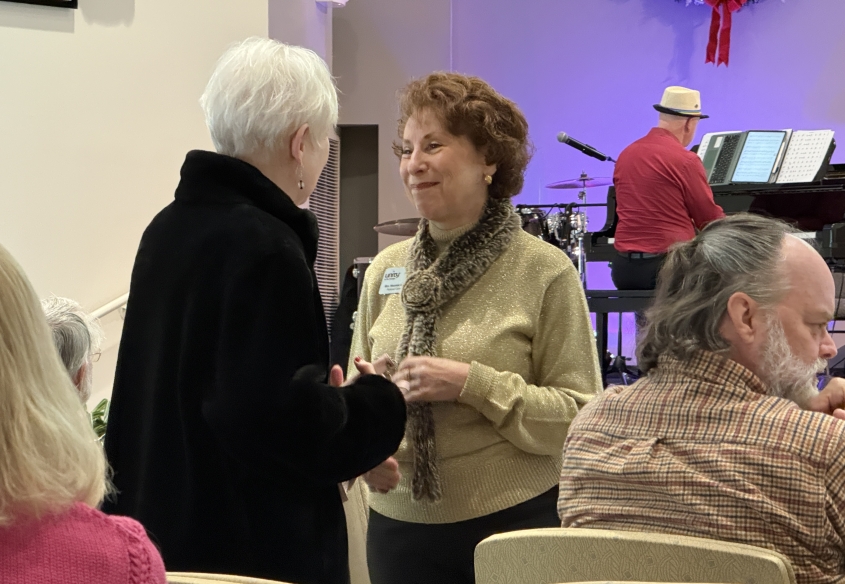 Rev Meemie Lohmueller wearing green sweater and scarf comforting a congregant