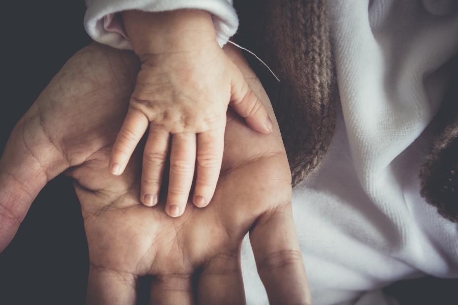 a baby's hand resting on the palm of an adult male hand