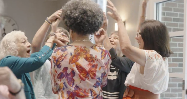 5 women gathered in a circle with arms in the air in spontaneous celebration
