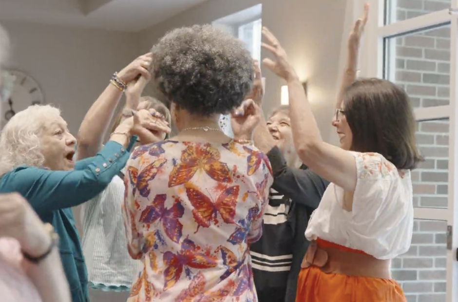 5 women gathered in a circle with arms in the air in spontaneous celebration