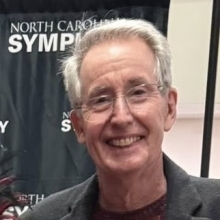 image of man with grey hair and wireless glasses smiling wearing dark shirt and sportcoat