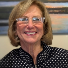 Beth Briggs wearing glasses, black and white polka dotted blouse