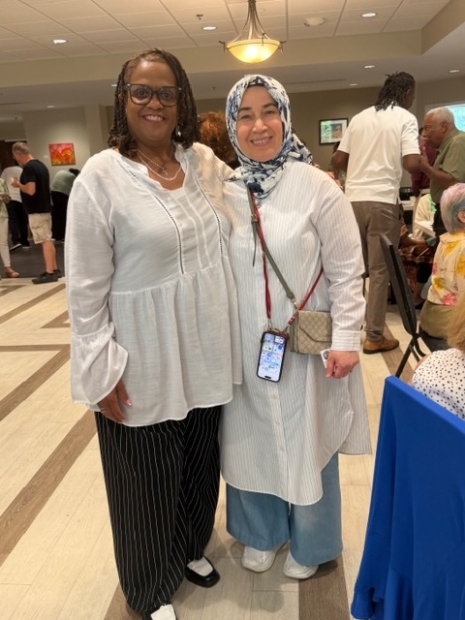 Rev Tami Johns wearing white flowy blouse and black pants. Woman dressed in muslim headdress, and white flowy blouse.
