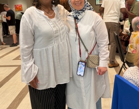 Rev Tami Johns wearing white flowy blouse and black pants. Woman dressed in muslim headdress, and white flowy blouse.